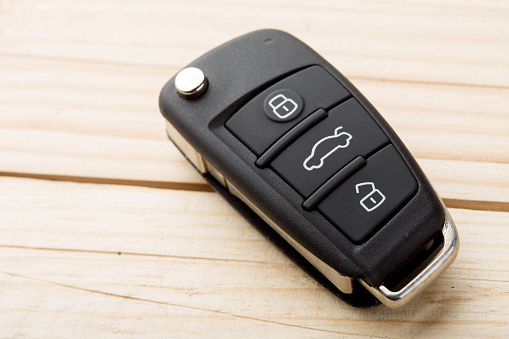 Car key and security remote on the wooden table, concept for rent or buy a new car