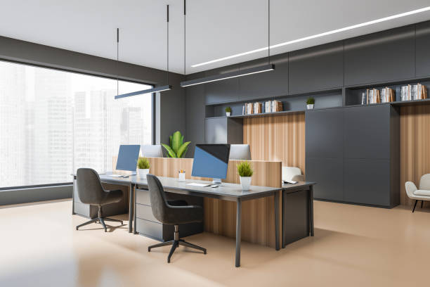 istock Corner view on dark office interior with tables with desktops 1398626127