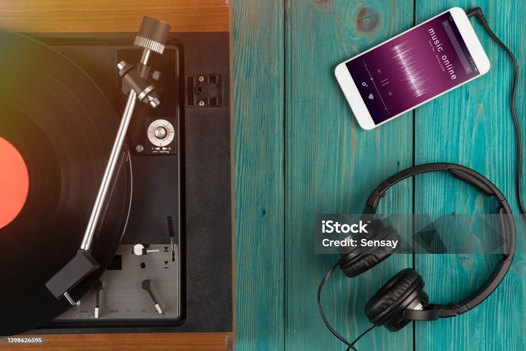 Listen music online concept - online music player app on smartphone with vintage turntable and headphones Listen music online concept - online music player app on smartphone Above Stock Photo