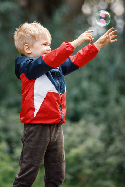 istock Very happy kid trying to catch soap bubble 1398630062
