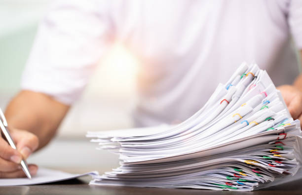 istock Man in white shirt sign contract agreement documents in Stack of Group report papers clipped in color clips in fair light, business, legal law and education concept 1398633810