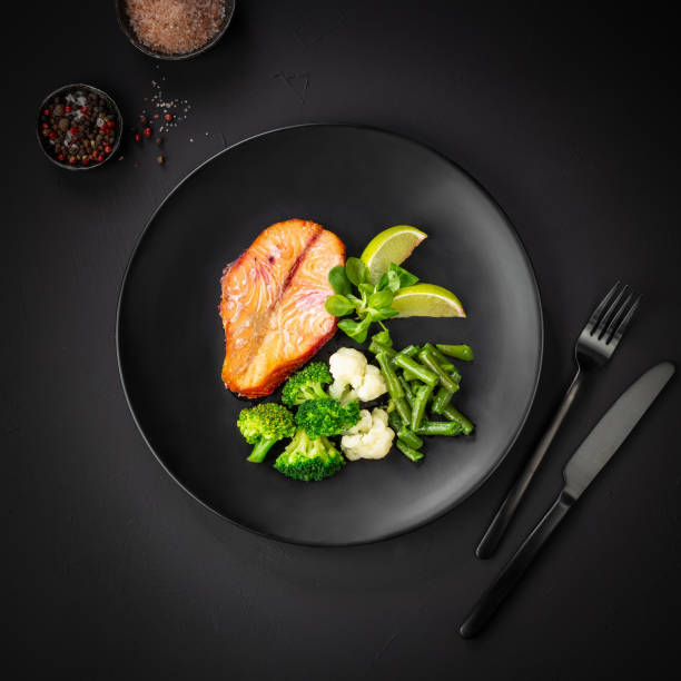 istock Baked salmon with vegetables (broccoli, cauliflower and green beans) on black background. Mediterranean diet concept. Flat lay, top view, copy space 1398633862