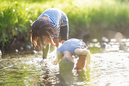 A brother and his sister are playing and having fun in a river in nature.