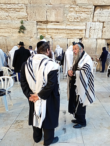 At the starting of the day, during the morning prayers, a man talks to his Rabbi at the holy Wailing Wall in the Old city of Jerusalem.