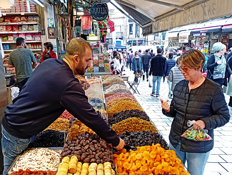 A market vendor preparing  a bag of fresh nuts and dried fruits for his customer at Mahane Yehuda food market in Jerusalem.