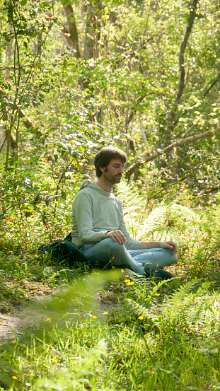Young white man meditating in the woods