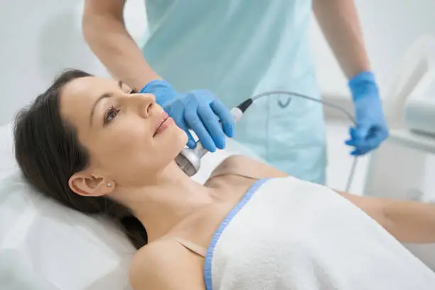 Photo of Beauty expert using RF-therapy on female neck