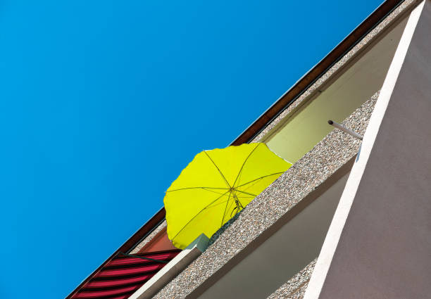 Low angle view of a contemporary residential building in Wetzikon, Switzerland, with a yellow sunny umbrella on the balcony.