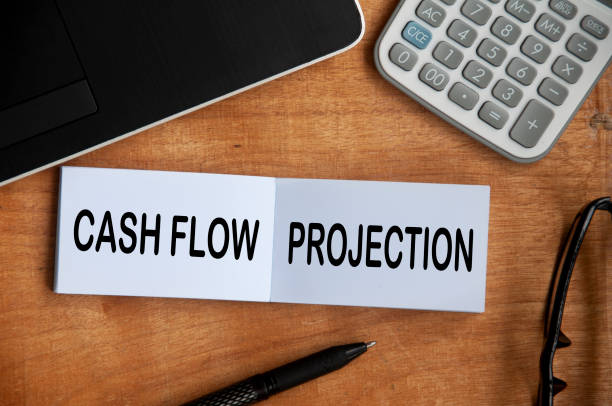 istock Cash flow projection text on notepad with calculator, pen and laptop background. Business concept 1398647711