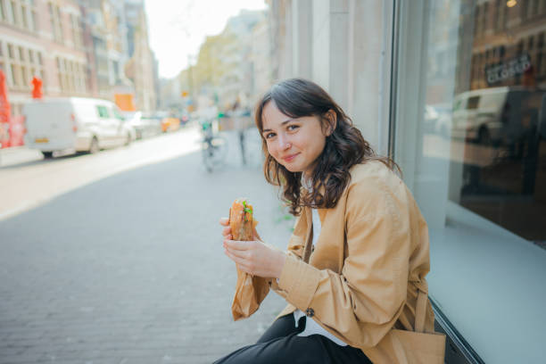 mulher sentada e comendo panini fora da loja - freedom sandwich bread food - fotografias e filmes do acervo