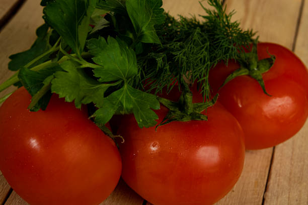 Red tomatoes, dill and parsley on a wooden table. High quality photo