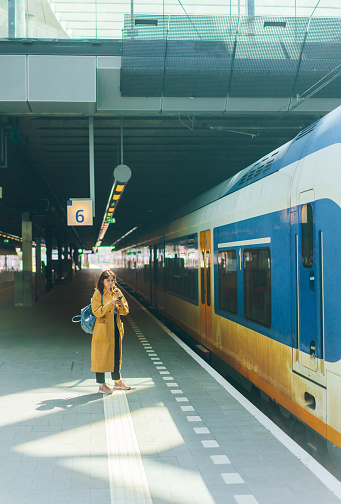 Young Caucasian woman  talking on the phone while waiting for the train on railway station