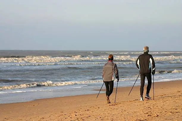 Two adults Nordic Walking on the beach