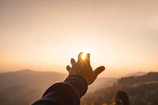 istock Young man hand reaching for the mountains during sunset and beautiful landscape 1398652802