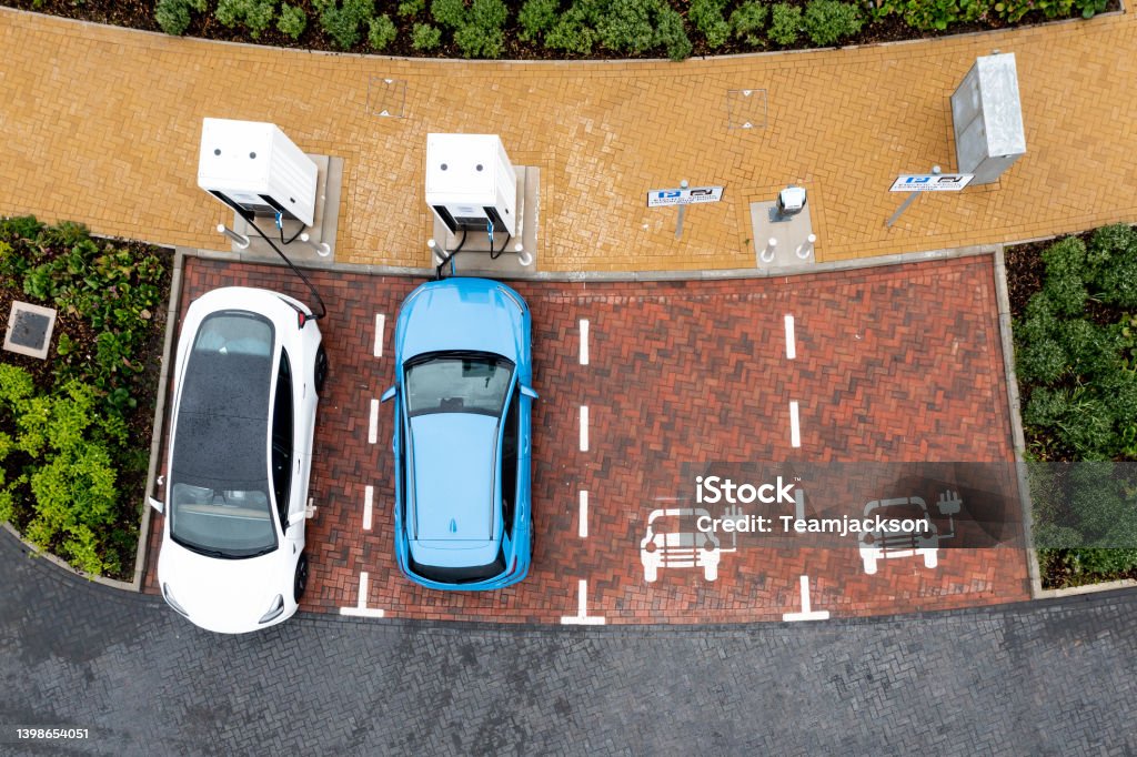 Aerial view directly above electric car being charged An aerial view directly above electric cars being charged at a motorway service station car charging station High Angle View Stock Photo