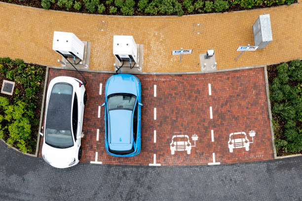 Aerial view directly above electric car being charged An aerial view directly above electric cars being charged at a motorway service station car charging station station stock pictures, royalty-free photos & images
