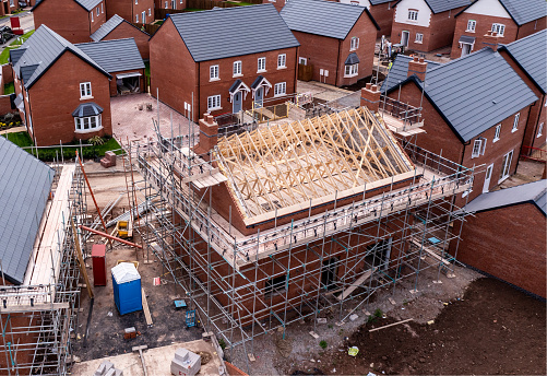 An aerial view of new build homes on a new housing estate with the roof exposed and wooden rafters and beams showing