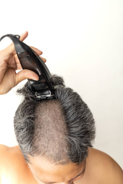 istock Handsome gray-haired man is cutting hair himself. 1398658077