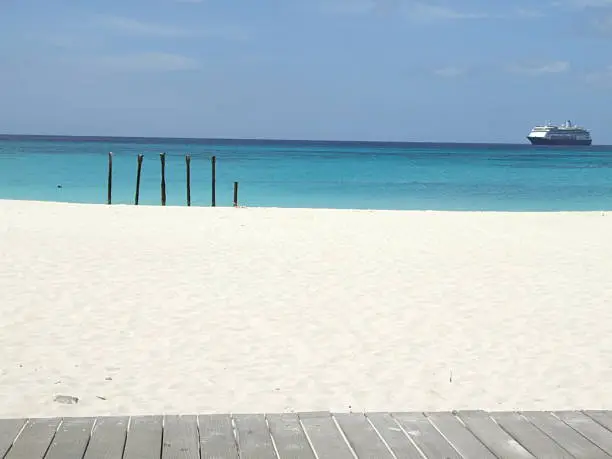 A cruiseship passing by on the horizon with a clear blue sky and blue sea.