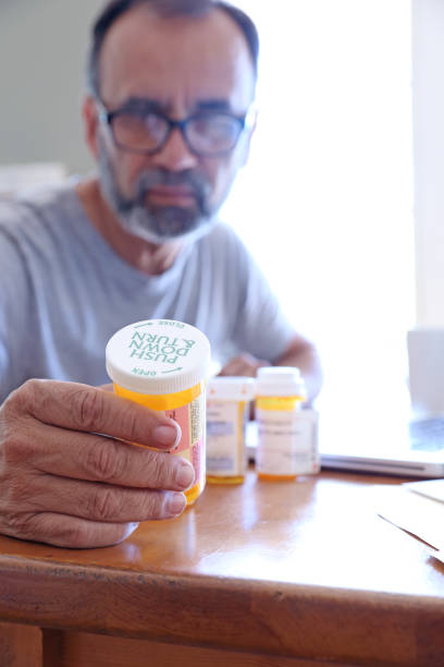 istock Hispanic Man Sitting At Dining Room Table Reading His Medication Label 1398660836