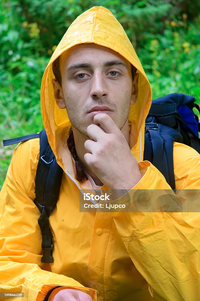 Turysta z plecakiem w żółty płaszcz Odpoczywać - Zbiór zdjęć royalty-free (Adolescencja)