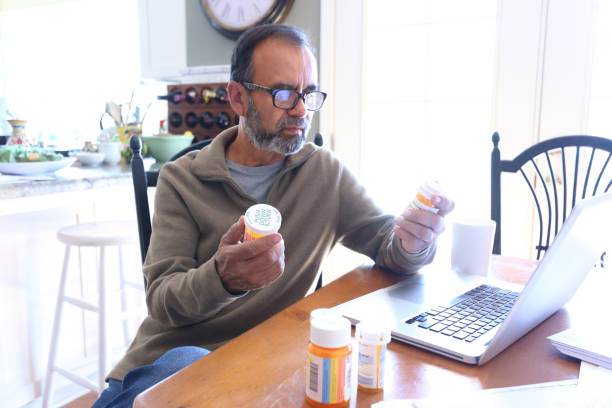 istock Hispanic Man Sitting At Dining Room Table Reading About His Medication On His Computer 1398662334