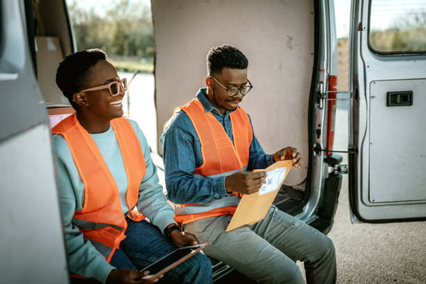 istock Young smiling delivery workers sitting on the back of delivery van 1398663289