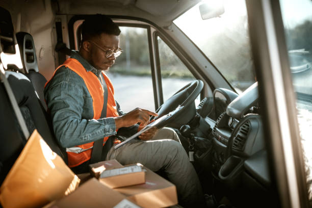 młody poważny kurier sprawdzający dokumenty w samochodzie dostawczym - delivery van delivery person messenger men zdjęcia i obrazy z banku zdjęć