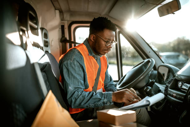 istock Young serious courier checking his paperwork inside of a delivery van 1398663363