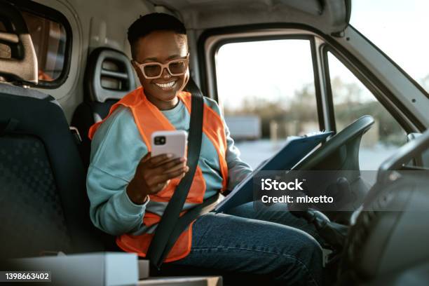 Young Smiling Female Delivery Driver Texting While Working Stock Photo - Download Image Now
