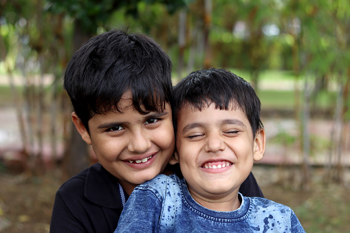 Elementary age cheerful sibling laughing portrait together outdoor in nature.