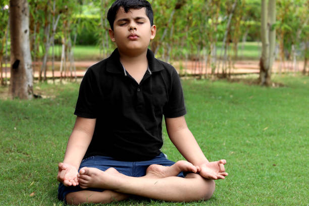 Elementary age child practicing yoga in the park outdoor in nature during springtime.