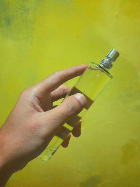 a person's hand holding a perfume bottle