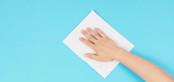 istock Hand is wiping and hold white paper tissue on blue background. Empty space for text . Top down view. 1398665589