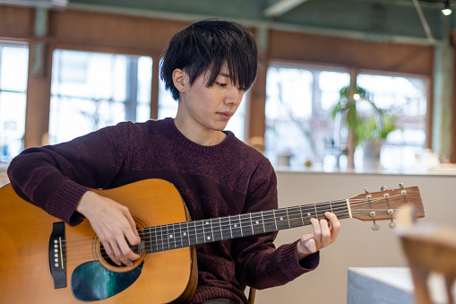 A man in his twenties practicing playing the guitar
Performing arts repeatedly practice