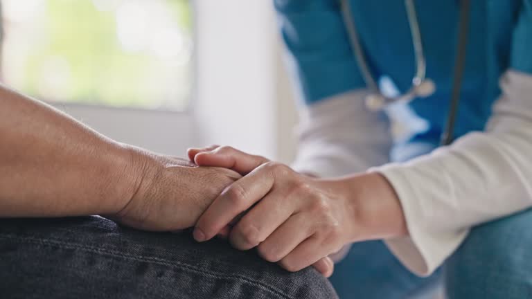 Female Doctor or Nurse holding hand of senior man patient, closeup