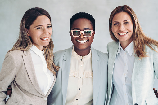 Group of smiling businesswomen standing together arm in arm