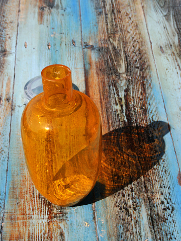 A colourfull bottle used for adding water to Pernod on a table