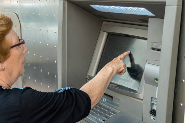 istock Elderly woman using an ATM in the street 1398671336