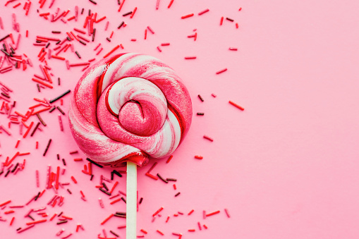 Colorful lollipop with sugar topping isolated over pink background. Flat lay. Copy space. Minimal concept