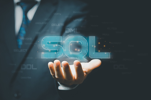 Businessman hand showing SQL word and SQL (Structured Query Language) code on background.