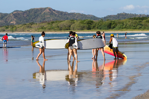 January 08th, 2016. Tamarindo, Costa Rica. Members of a surf school are walking on the beach. Tamarindo has a lot of tourist looking for the big waves, and is one of the places where you can take some surf lessons.