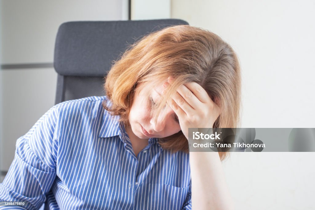 cephalgia, migraine, headache, woman holds her head with her hand,suffers from pain at work in the office 35-39 Years Stock Photo