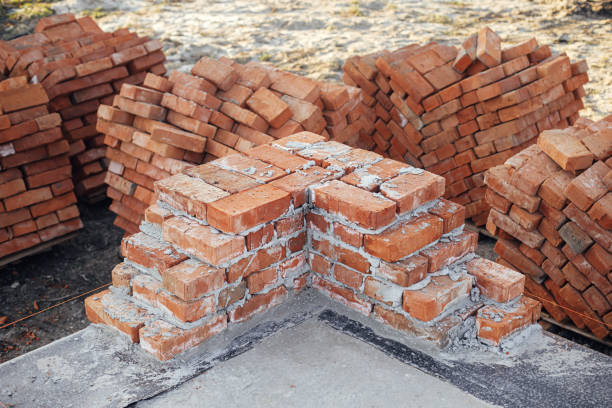 istock Bricks masonry with cement on concrete foundation close up, process of house building. Red bricks for laying on concrete foundation. Building materials at construction site 1398676302