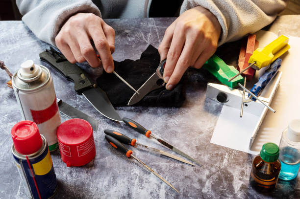 sharpen the serrated knife. sharpen a knife with a saw. tool in hand. oil, grindstones and tools on the table. - oil filed imagens e fotografias de stock