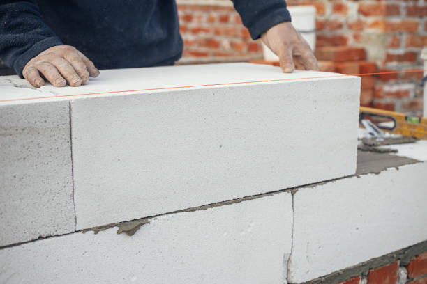 istock Masonry. Worker laying autoclaved aerated concrete blocks. Builder installing white blocks close up. Process of house building at construction site 1398676650