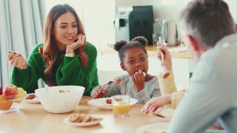 Cheerful multinational family eating breakfast