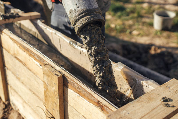 bauherren gießen beton mit pumpwagen in holzschalung mit bewehrung. arbeiter, die beton in schalungen für das fundament gießen. baustelle, prozess des hausbaus - formworks stock-fotos und bilder