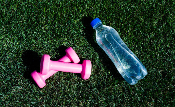 Healthy lifestyle concept. water balance in body while workout. barbells and bottle on green grass. sport tool and equipment. dumbbells in park. hydration after fitness. healthy lifestyle. concepto de estilo de vida saludable. equilibrio hídrico en el cuerpo durante el entrenamiento. barras y botella sobre hierba verde. herramienta y equipo deportivo. mancuernas en el parque. hidratación después de la aptitud física. estilo de vida salud