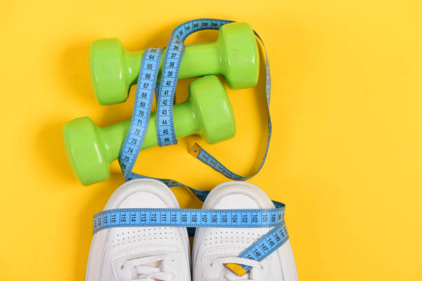 istock Sneakers with measuring tape on yellow background 1398682261